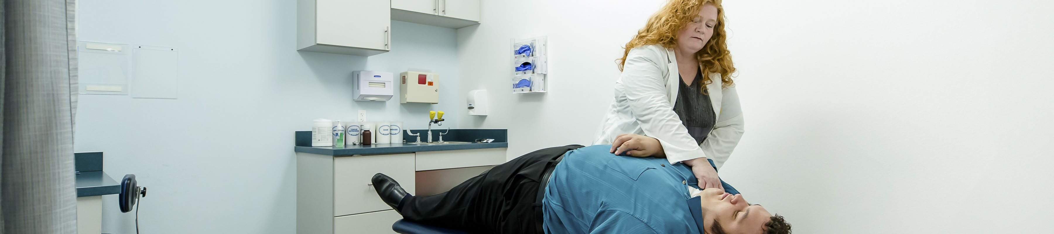 A patient lays on an exam table in a doctors office while a physician examines their neck